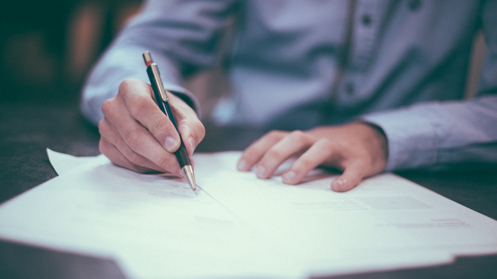 Main signant un document juridique au stylo